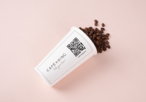 Ein Kaffee to Go Becher mit Branding und Kaffeebohnen als Inhalt