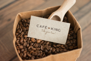ein Sack mit gerösteten Kaffeebohnen, darauf liegt eine Visitenkarte