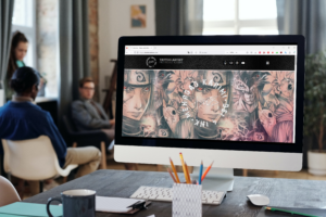 Ein Monitor steht auf einem Schreibtisch im Hintergrund sitzen Menschen